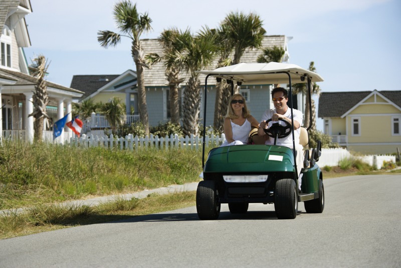 Golf Carts Port Aransas: A vacationing couple drives their golf cart through a neighborhood in Port Aransas.